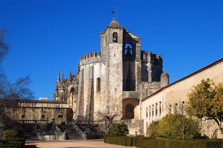 The majestic Convent of Christ in Tomar under a clear blue sky, showcasing its stunning medieval architecture.