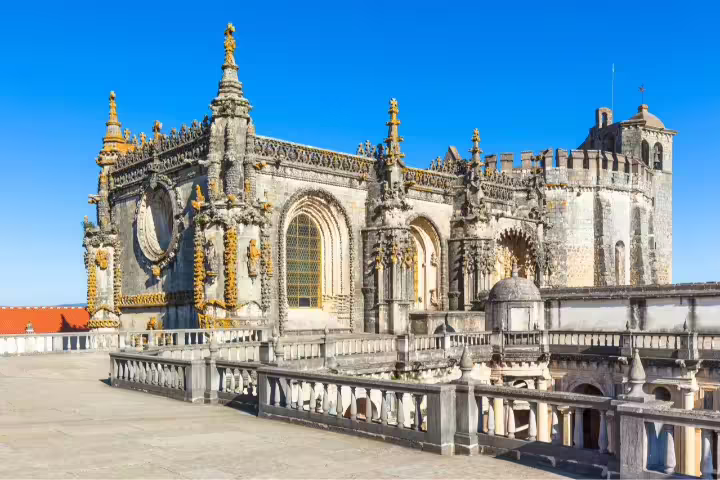 Historic Convent of Christ, Tomar, Portugal under clear blue skies, showcasing intricate Gothic architecture on self-drive tour.