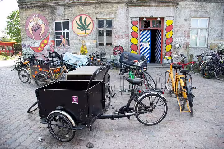Colorful bicycles and street art outside a vibrant Christiania building in Copenhagen's Vesterbro and Christianshavn tour.