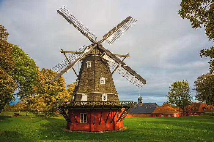 Historic windmill surrounded by lush greenery on a sunny day, featured in the Highlights and Secrets of Copenhagen Tour.