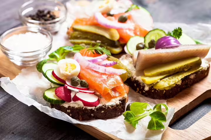 Open-faced sandwiches with smoked salmon, herring, and fresh vegetables on rye bread, featured on a Copenhagen food tour.