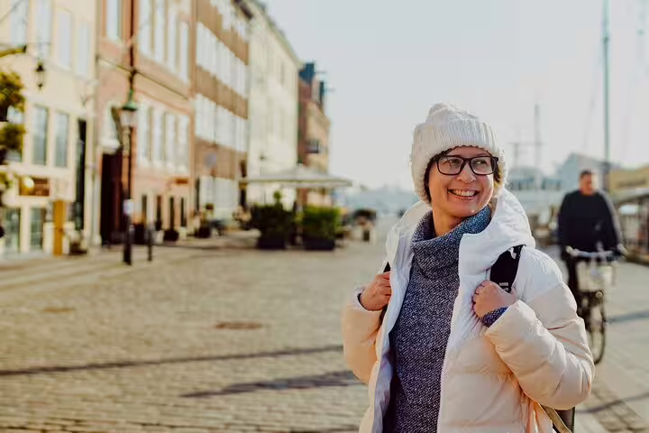 Smiling tourist explores charming streets of Copenhagen on a private walking tour, highlighting the city's secrets and attractions.