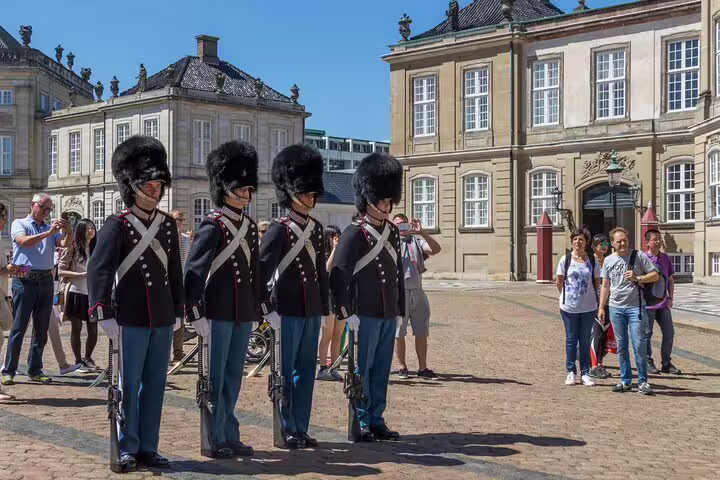 Royal guards in traditional uniforms stand at attention during the Changing of the Guard ceremony in Amalienborg Square, Copenhagen.