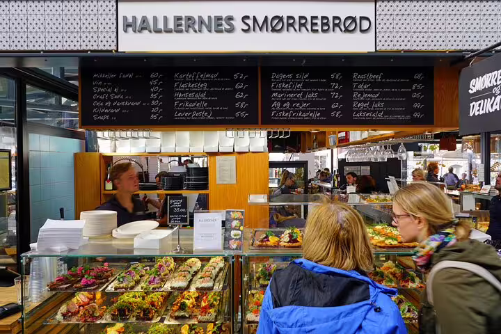 Tourists explore vibrant Danish smørrebrød options at a bustling food stall in Copenhagen, showcasing Scandinavian culinary delights.