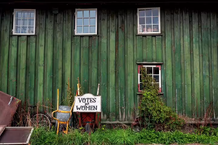 Green rustic building with "Votes for Women" sign, showcasing Vesterbro and Christianshavn's unique charm on Copenhagen tour.