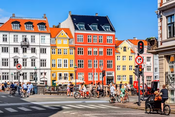 Colorful historic buildings and cyclists at Nyhavn canal street in Copenhagen, Denmark on a sunny day
