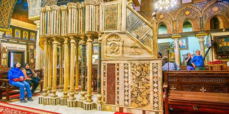 Ornate Coptic church interior in Old Cairo with carved pulpit and icons on Saint Simon Monastery tour