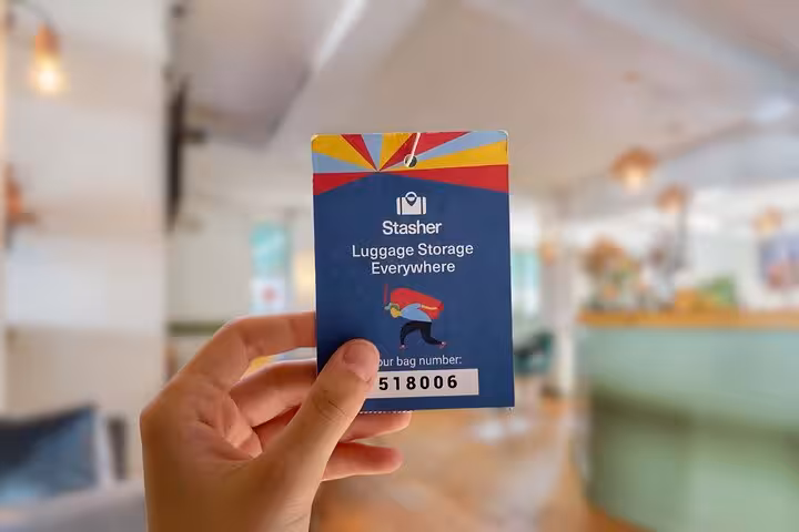 Hand holding Stasher luggage storage tag inside Cordoba location, easy check-in for secure baggage storage