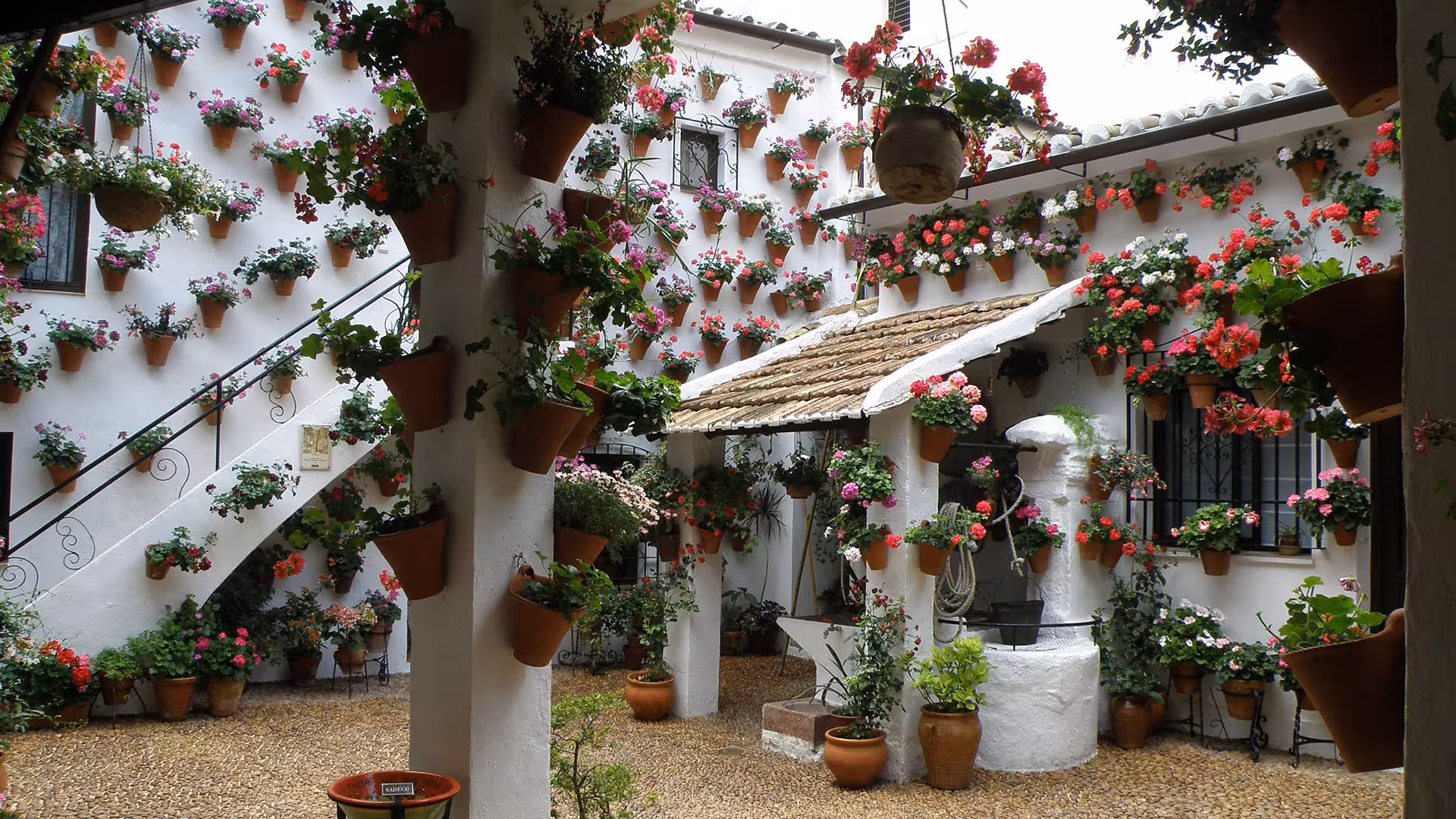 Picturesque Cordoba courtyard with cascading flowers in terracotta pots, epitomizing the Patios Festival's beauty.