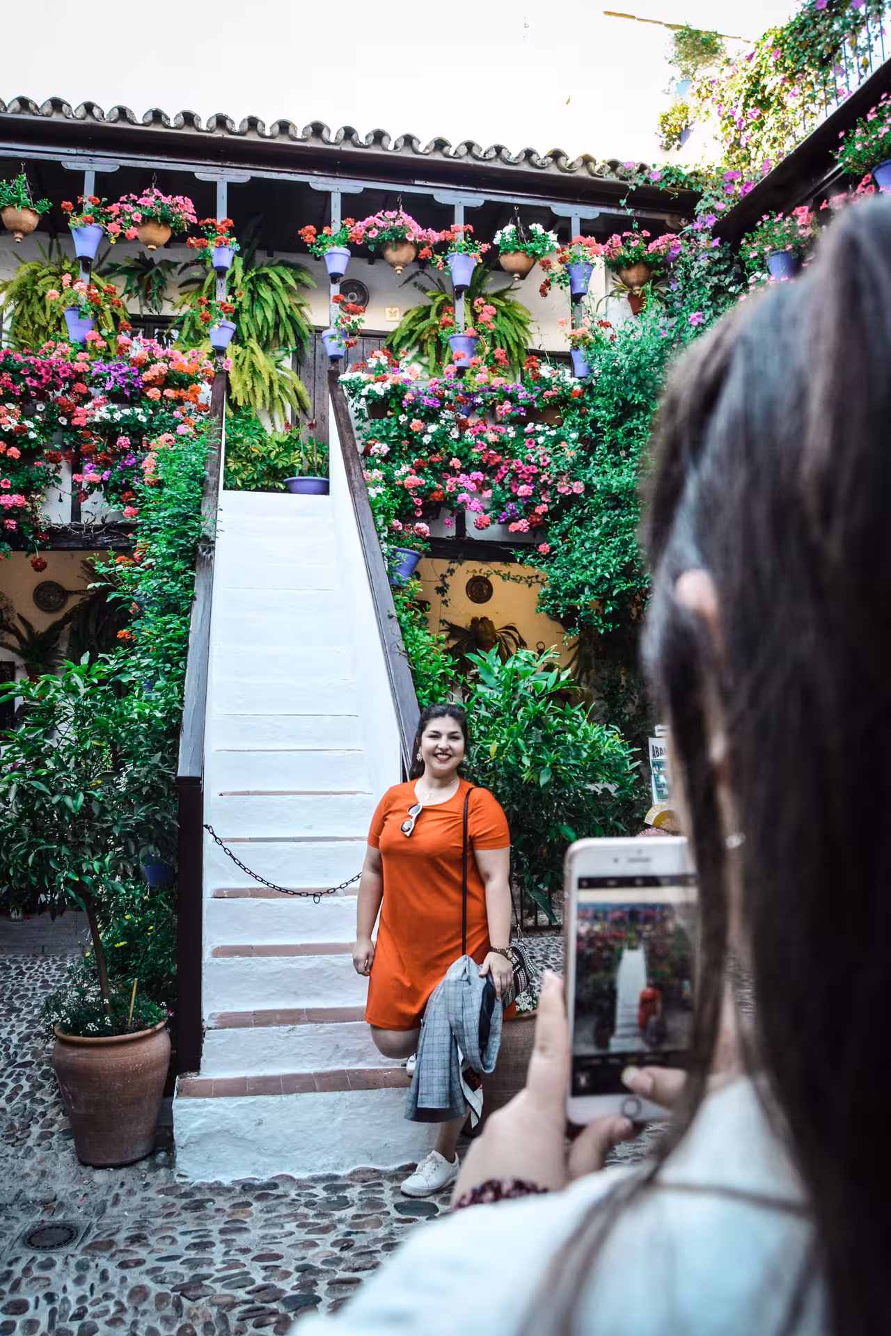 Visitor poses for a photo in a vibrant patio filled with colorful flowers during Córdoba's popular patio tour.