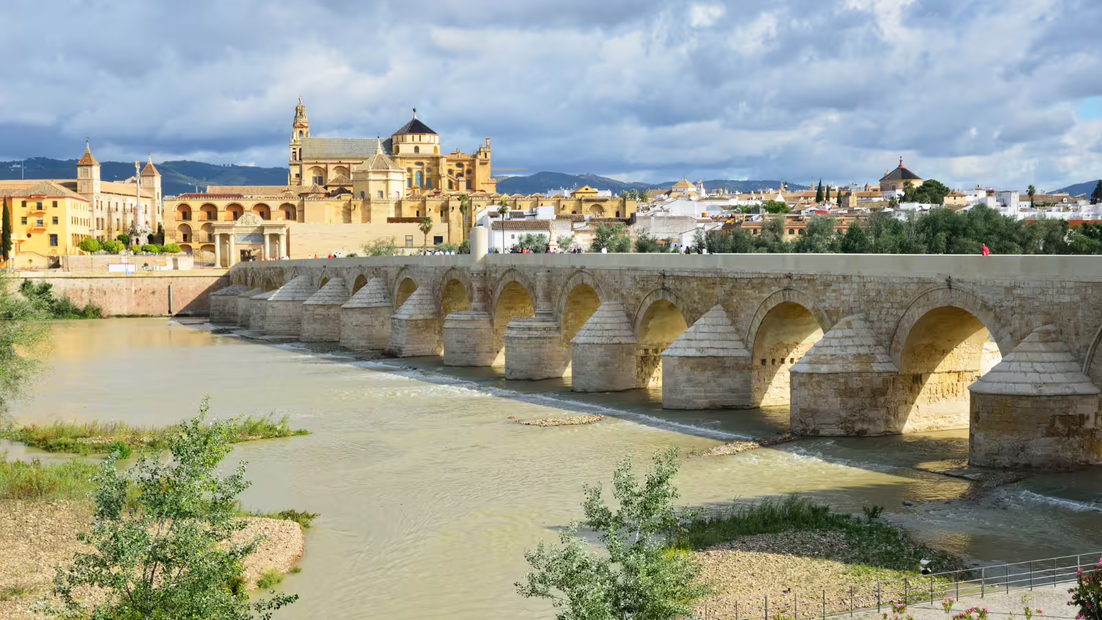Roman Bridge over the Guadalquivir with Córdoba skyline and Mezquita tower, featured on group walking tours