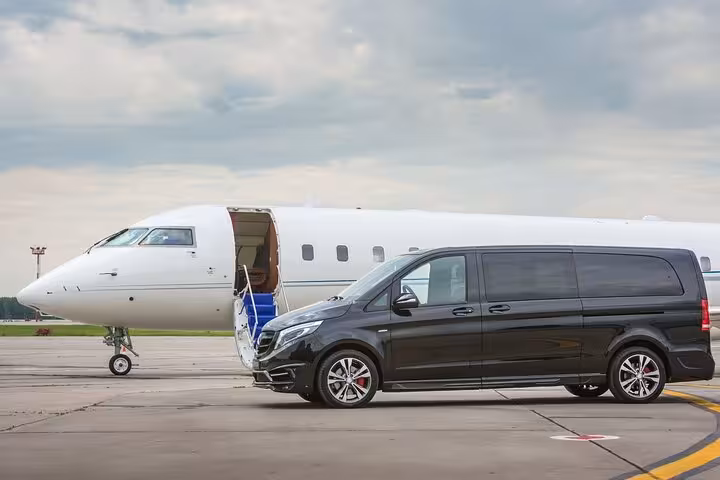 Luxury black van beside private jet on runway, Corfu private airport transfer to hotel or port service