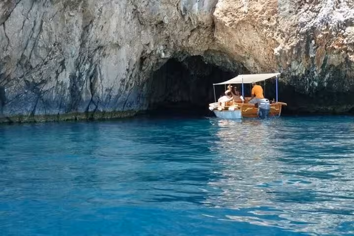 Small boat entering a sea cave at Paleokastritsa on Corfu private tour, exploring bays near Glyfada
