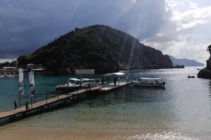 Private Corfu beach tour view with jetty and boats on turquoise bay below lush headland and sunlit sea