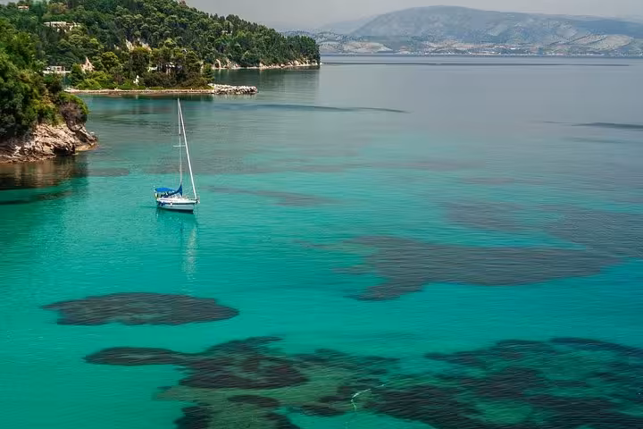 Sailboat on turquoise Corfu lagoon bay, scenic stop on private shore excursion for cruise guests