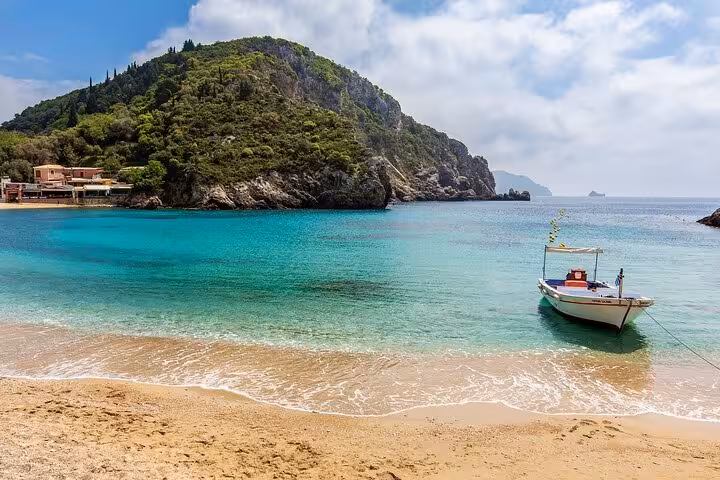 Turquoise Corfu bay with fishing boat and sandy beach, highlight of Corfu Beauty & the Beach private tour