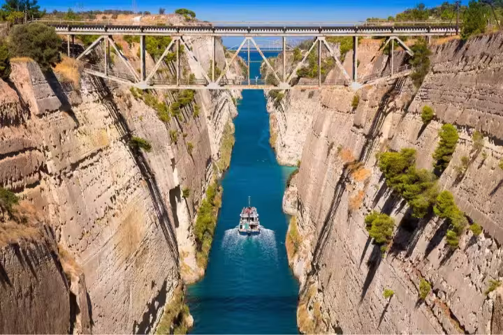 Boat navigating the stunning Corinth Canal in Peloponnese, Greece, under a scenic bridge, perfect for an awarded day trip.