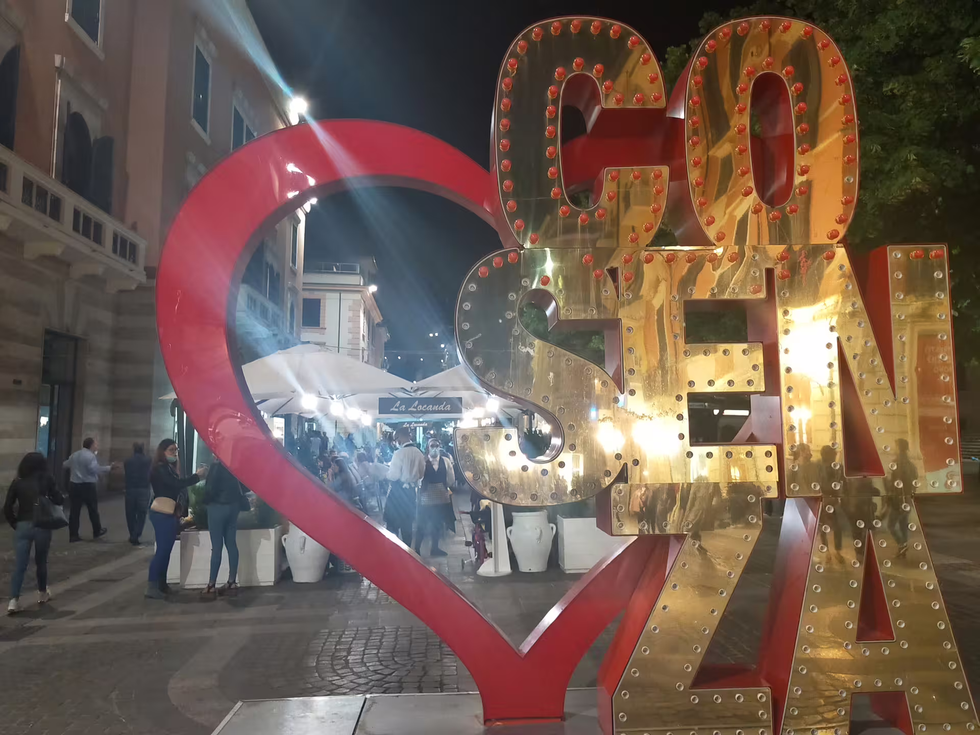 Nightlife in central Cosenza with illuminated I Love Cosenza sign, lively streets, cafés and locals enjoying the historic city