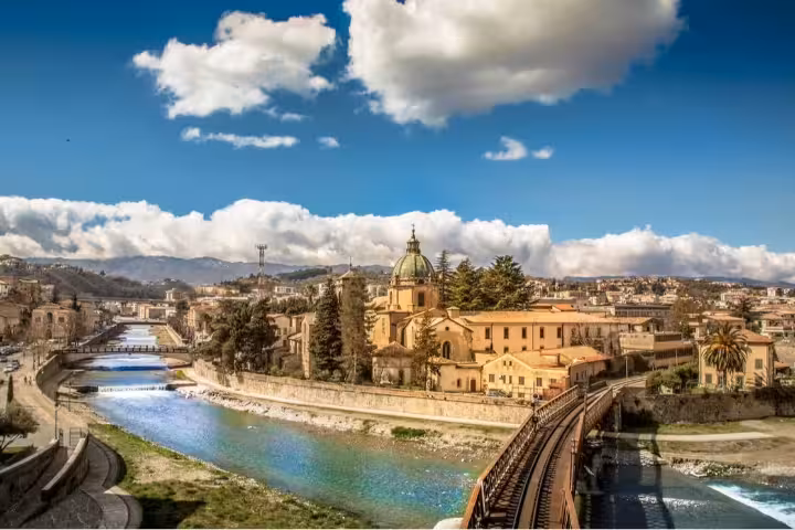 Panorama di Cosenza con fiume, ponte ferroviario e cupole barocche, punto di partenza del tour Calabria mitologica