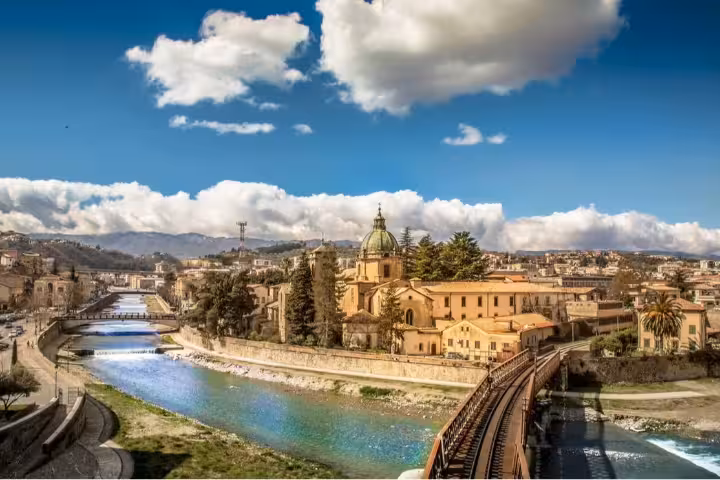 Panoramic view of Cosenza near Sila Park, with river, bridges and historic domes framed by mountains and blue sky