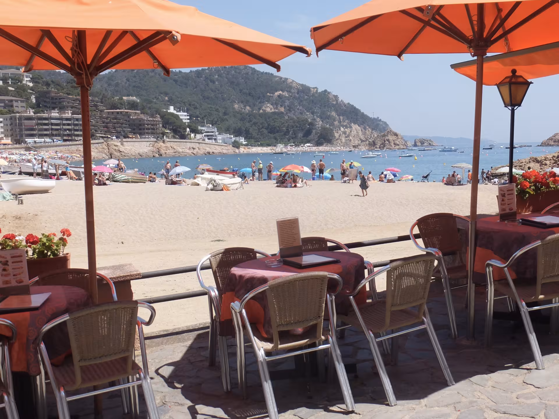 Seafront cafe terrace on Costa Brava beach trip from Barcelona, overlooking bay, boats and umbrellas
