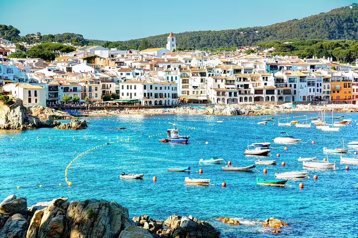 Charming coastal town of Costa Brava with colorful boats floating in the clear turquoise water.