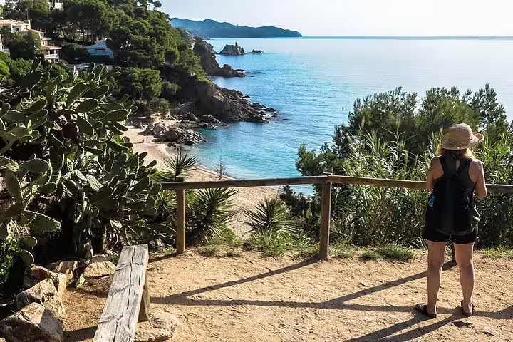 Woman admiring panoramic view of Costa Brava's rocky coastline and crystal-clear waters, perfect for nature lovers.