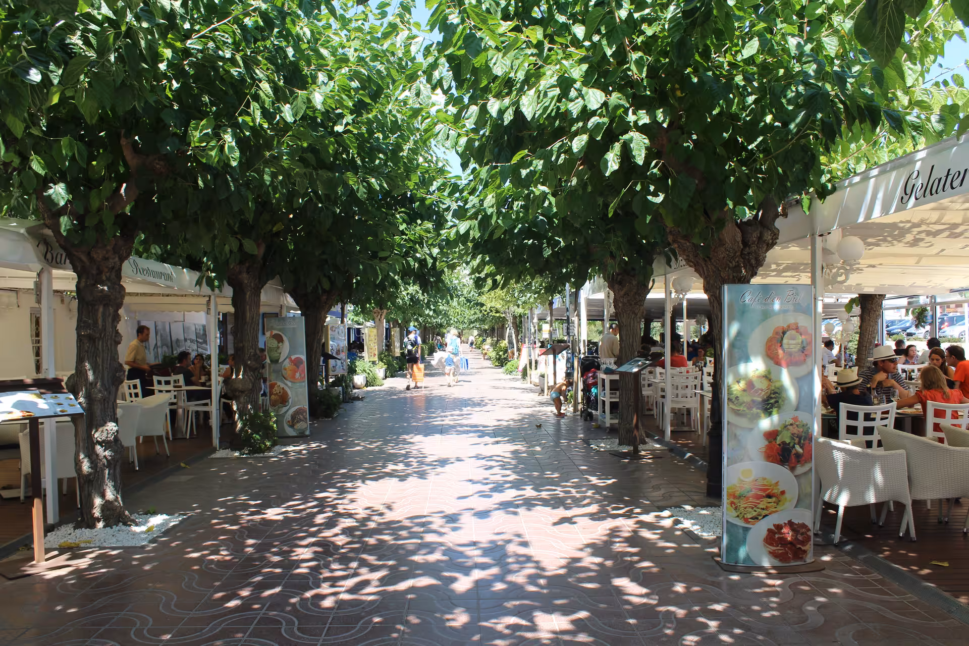 Tree-lined seaside promenade with cafes in Costa Brava, a relaxing day trip from Barcelona