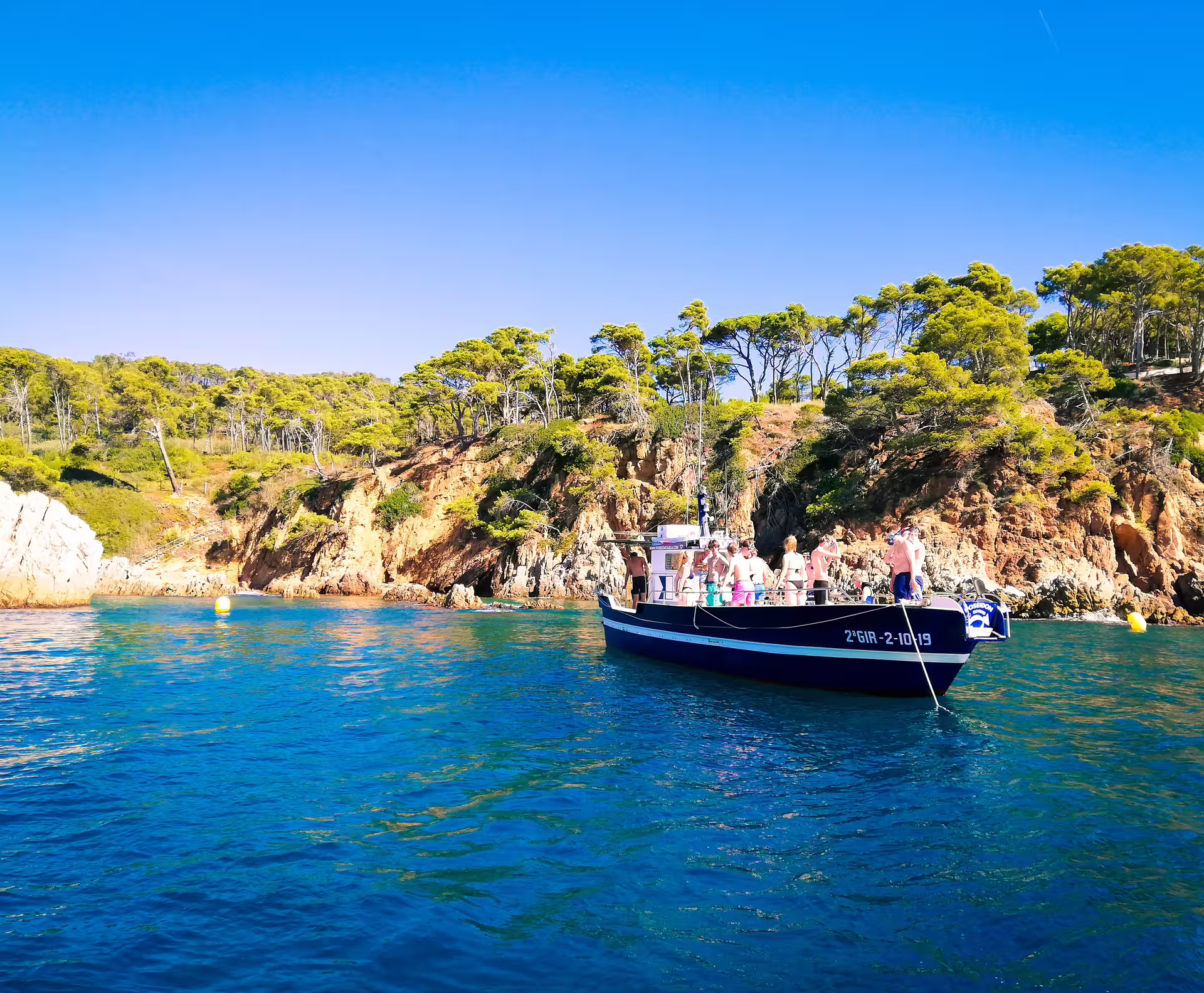 A boat anchored near the rocky coastline of Costa Brava, ideal for snorkeling adventures.
