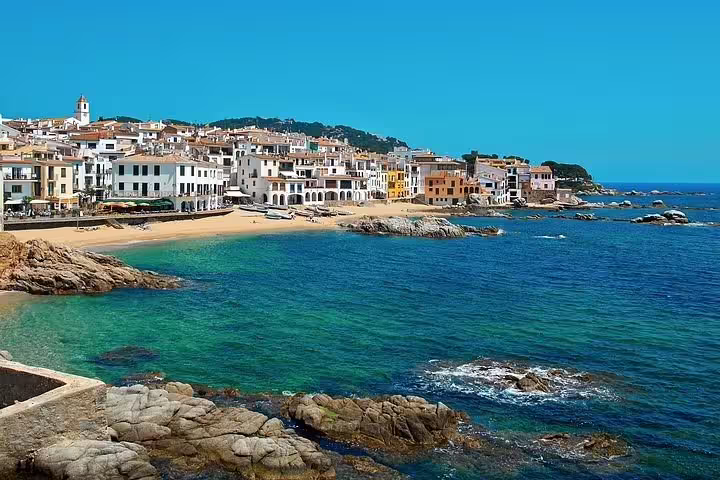 Charming coastal village view in Costa Brava with colorful buildings and clear blue sea, ideal for Girona tours.