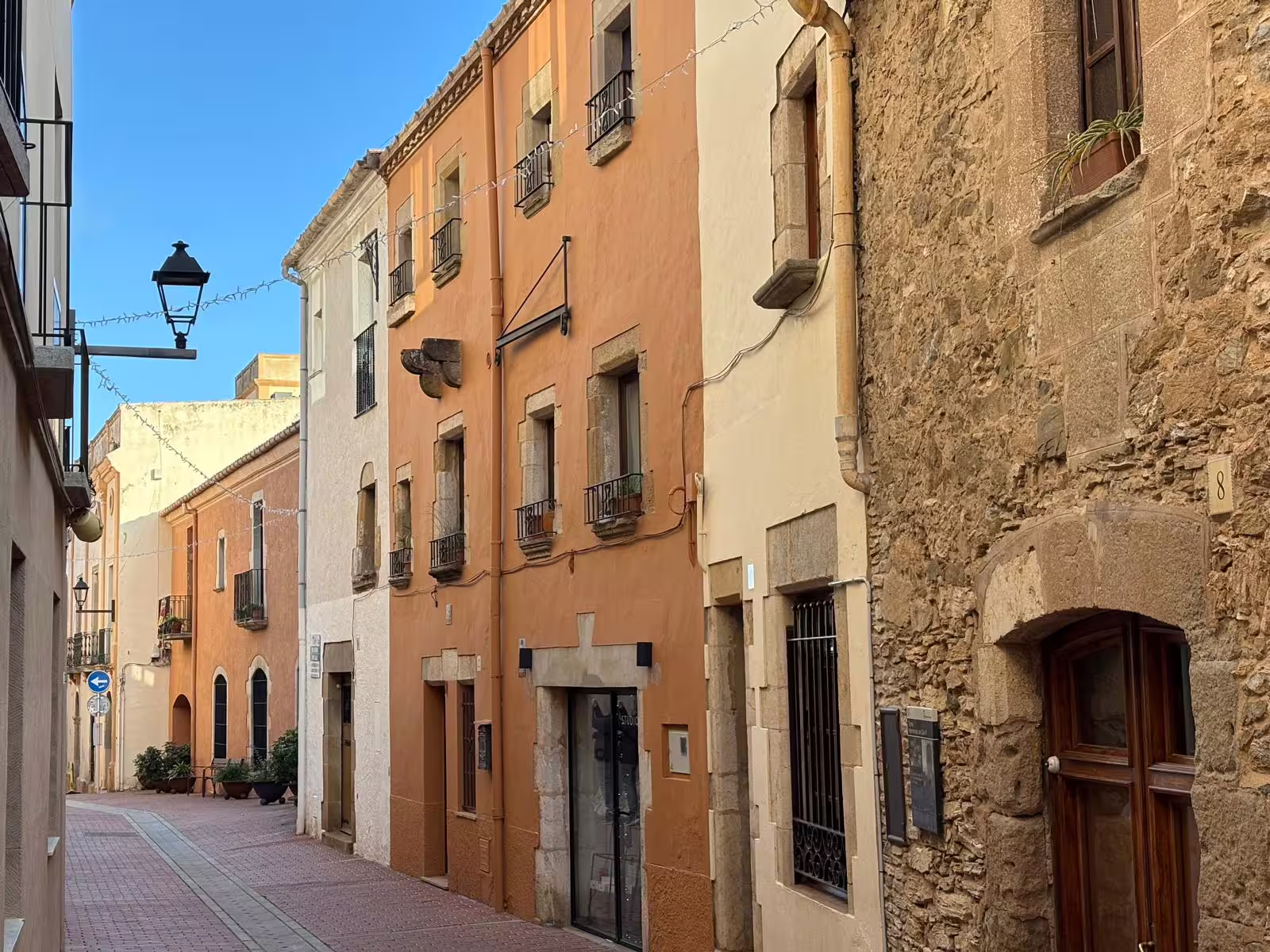 Charming street in a Costa Brava town with colorful facades and traditional architecture under a clear blue sky.