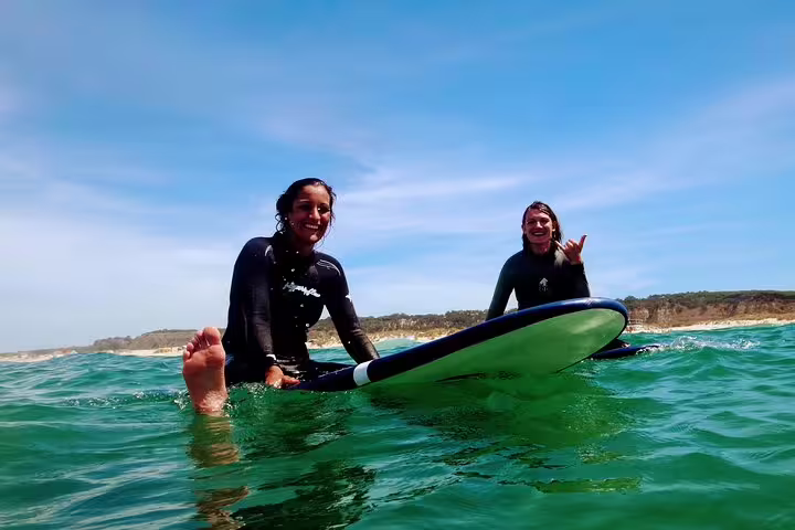 Two surfers enjoy the waves at Costa da Caparica, showcasing the vibrant surf culture near Lisbon on a sunny day.