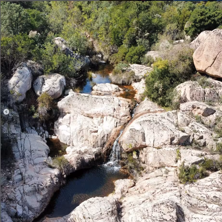 Scenic rock formations and a serene waterfall in Costa Rei's natural landscape, perfect for jeep tour exploration.