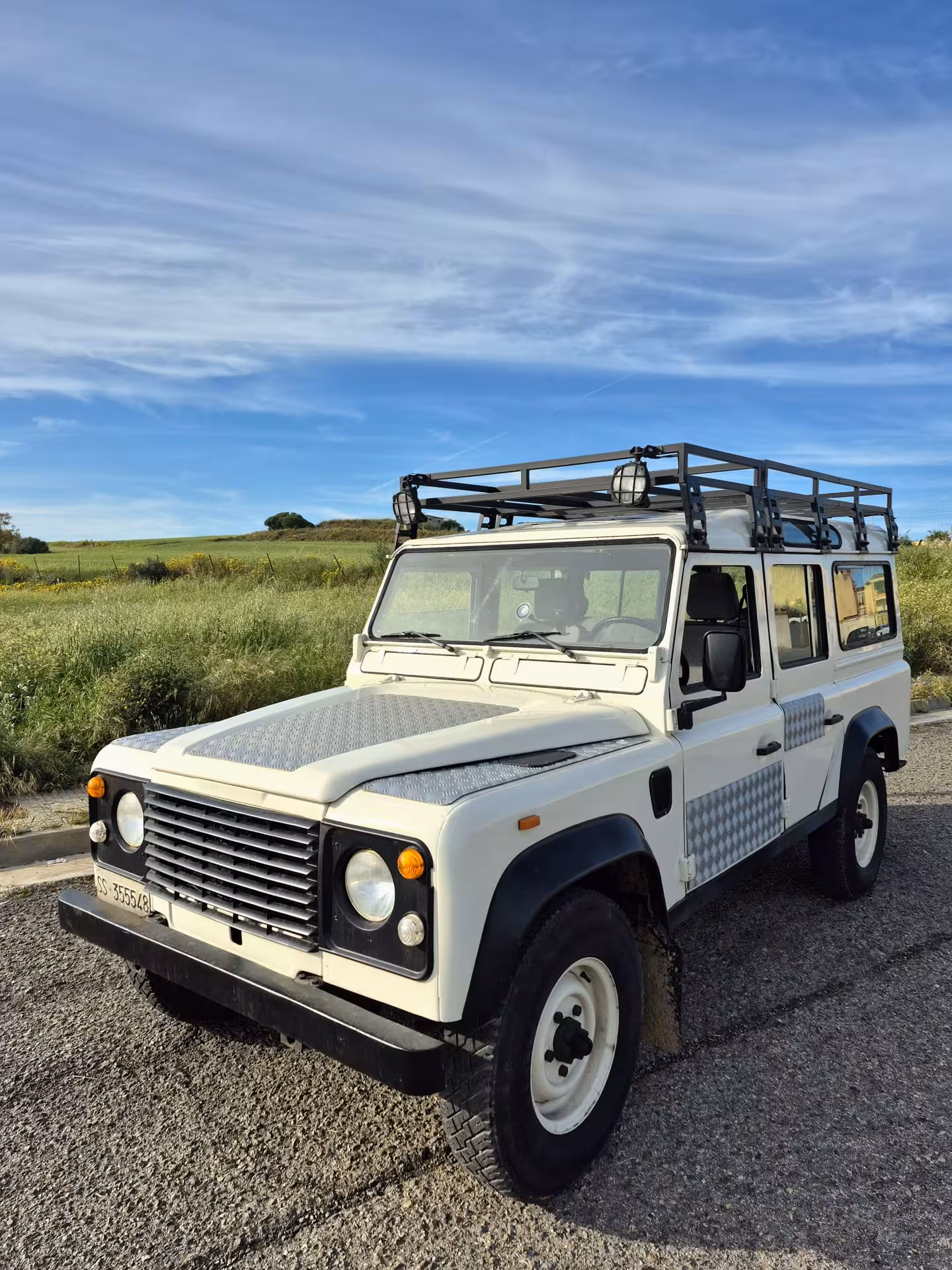 White jeep ready for adventure on the Costa Rei private tour, set against a backdrop of rolling green hills.