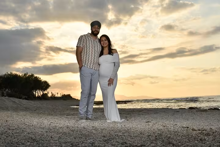 Couple posing on Ammoudara beach at sunset during private photoshoot, capturing romantic and serene moments by the sea.