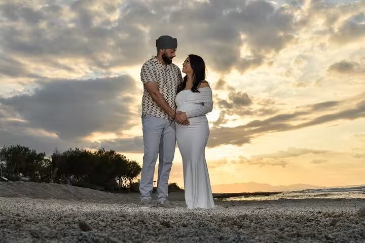 Couple standing on Ammoudara beach at sunset, sharing a loving gaze during a private photoshoot session.