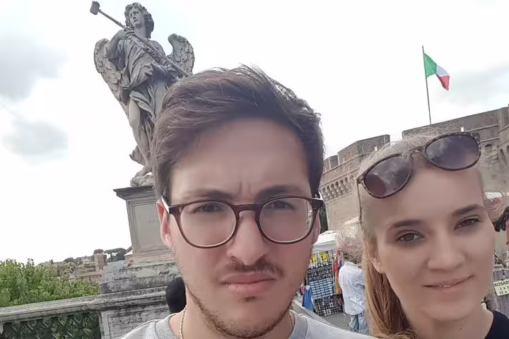 Couple selfie on Ponte Sant'Angelo with angel statue and Italian flag in Rome