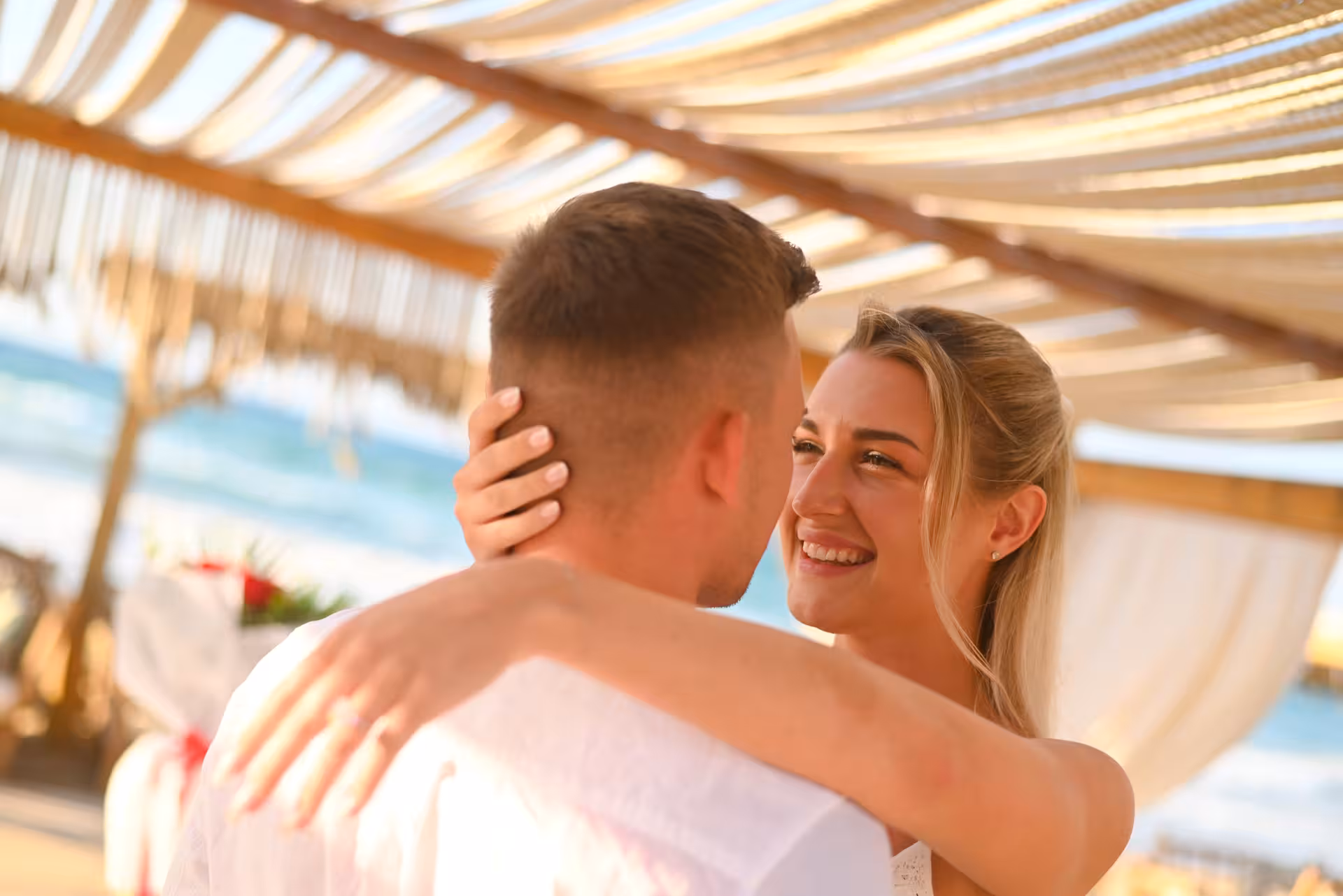 Couple in love embracing under a sunlit canopy at Heraklion Venetian Port, perfect for romantic anniversary photoshoots.