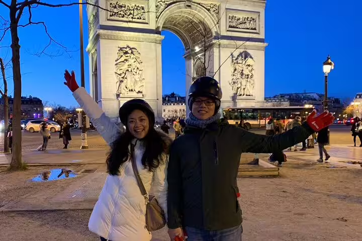 Couple posing by Arc de Triomphe at dusk before Paris Segway night highlights small group tour