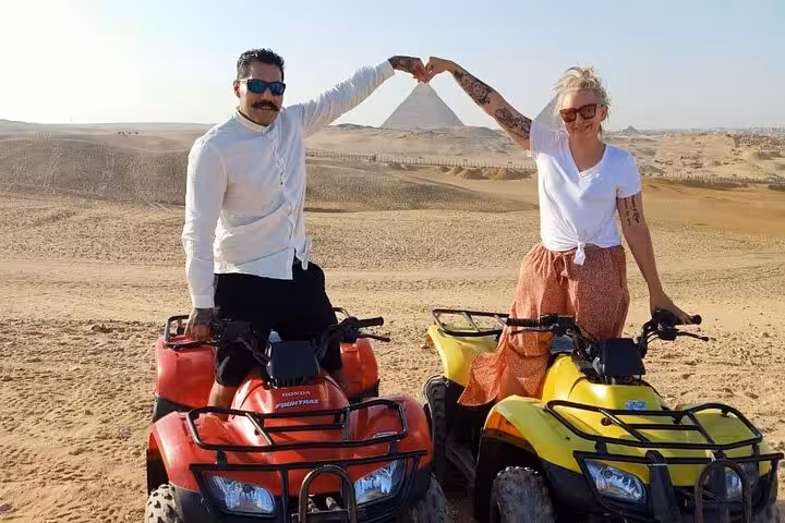 Couple on quad bikes posing by the Great Pyramid of Giza during private ATV safari, Sphinx visit, camel ride and lunch