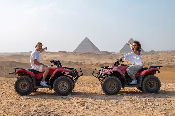 Couple on ATVs in the Cairo desert with Giza Pyramids view, quad biking adventure on Cairo tour excursion
