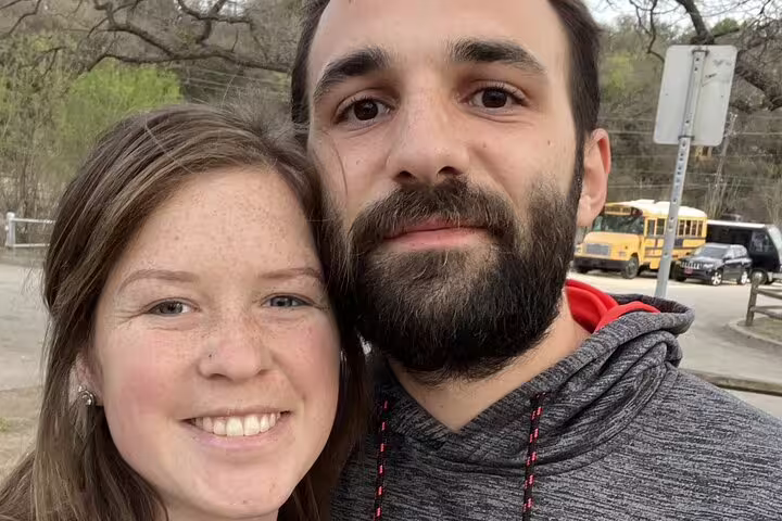 Couple smiling outdoors on Austin self-guided walking tour with yellow school bus in background