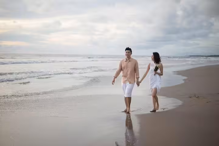 Couple walking hand in hand on a Bali beach during a private vacation photographer photo shoot at sunset