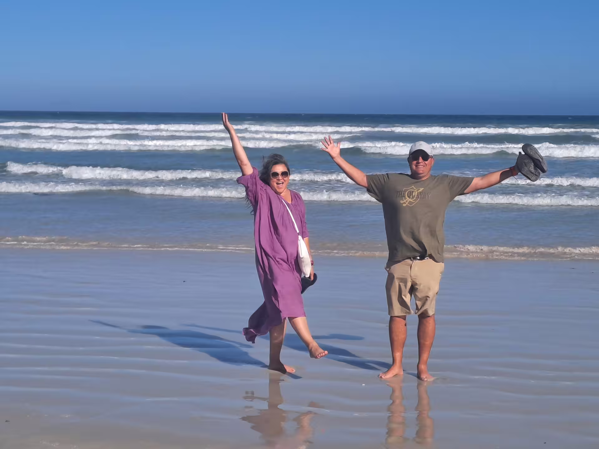 Couple enjoying a sunny day on a sandy beach with ocean waves at Cape of Good Hope tour.