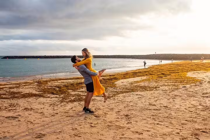 Couple embracing on sandy Tenerife beach in golden hour, private photoshoot with professional photographer in Tenerife
