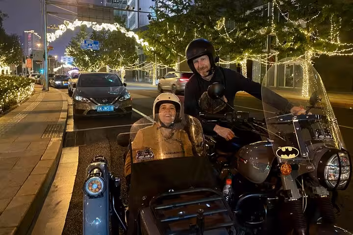 Couple on a sidecar tour, exploring Beijing's lit-up streets during a magical night ride.