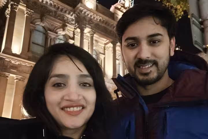 Couple smiling at night in front of a illuminated historic building in Belfast