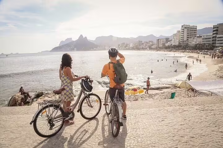 Couple enjoys stunning views of Ipanema Beach while on a bike tour along Rio's picturesque shoreline.