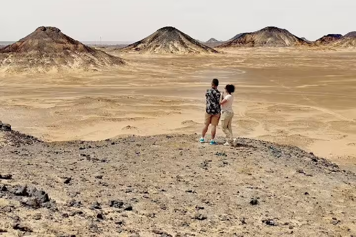Couple overlooking Black Desert landscape near Bahariya Oasis on a private 4-day White Desert safari tour