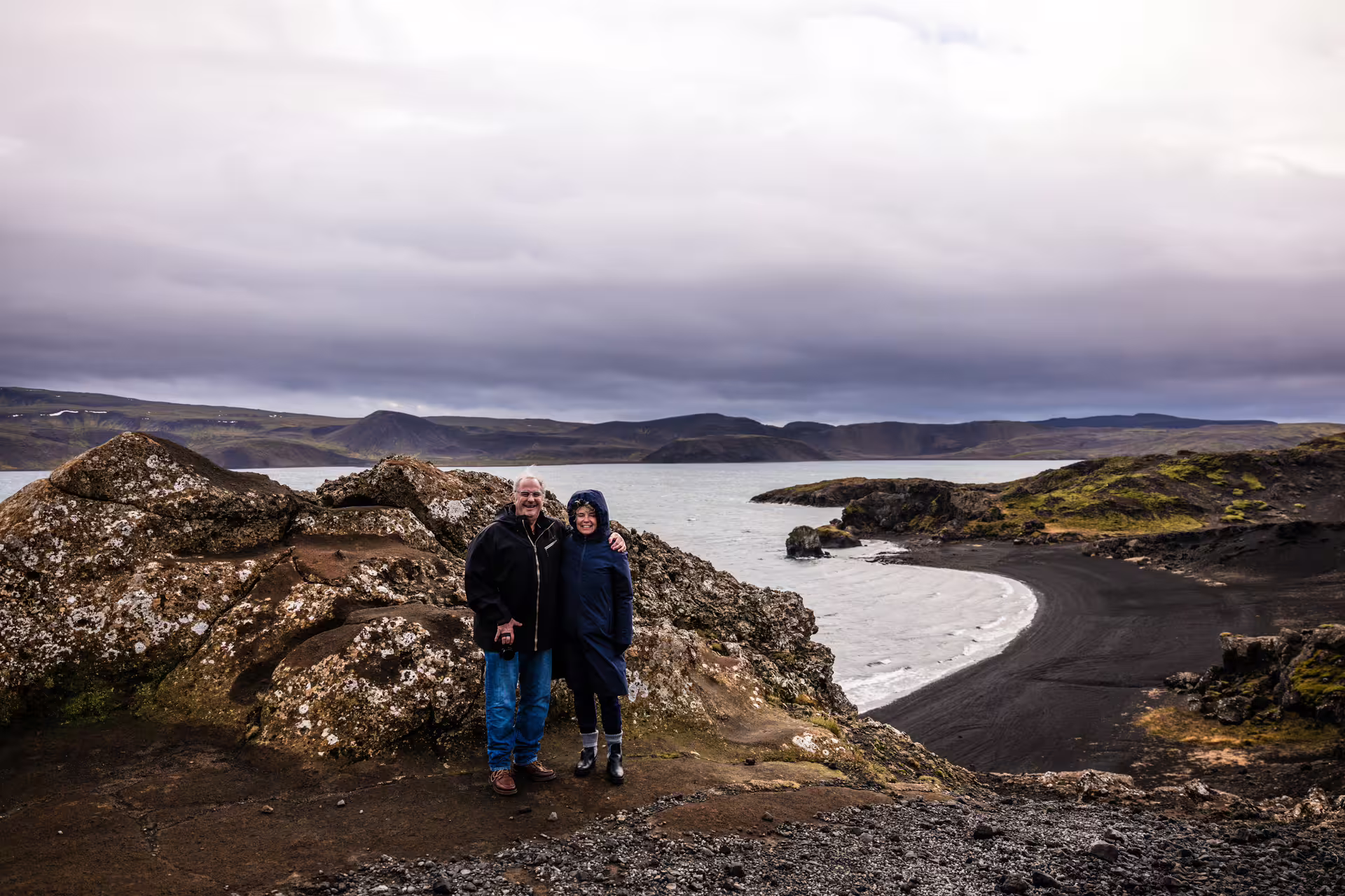 Couple posing by black sand beach and volcanic landscape on a Reykjanes day trip with professional photography tour